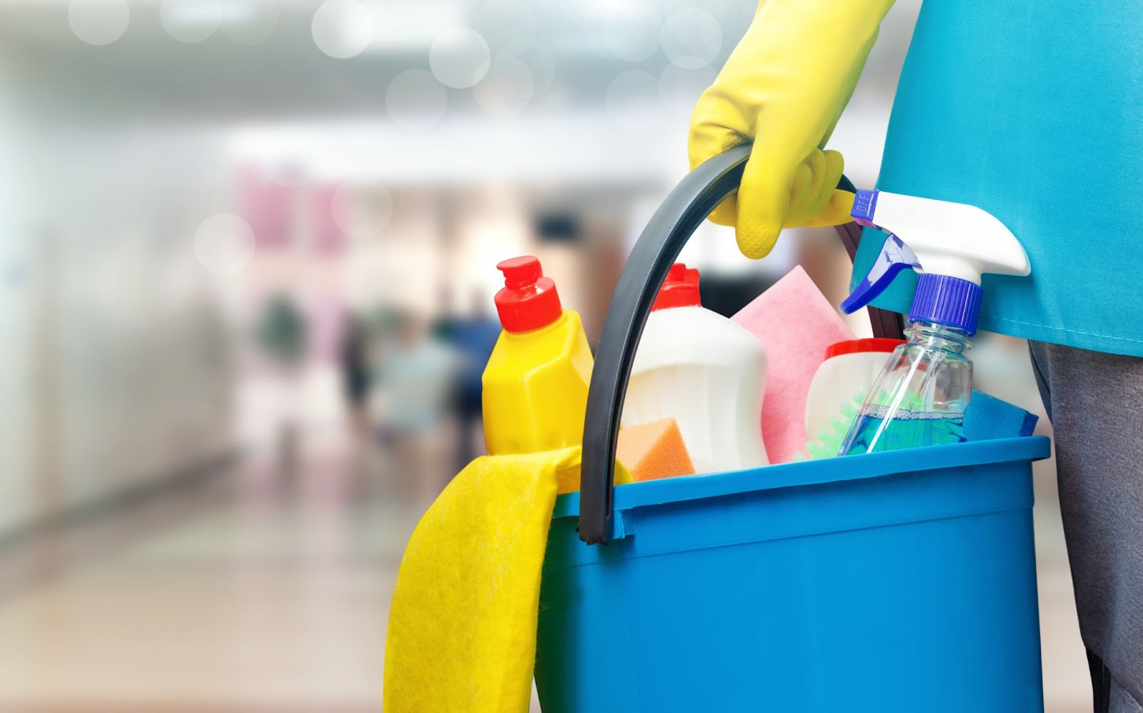 A business person stands with a bucket and cleaning products on blurred background after starting a new cleaning business.